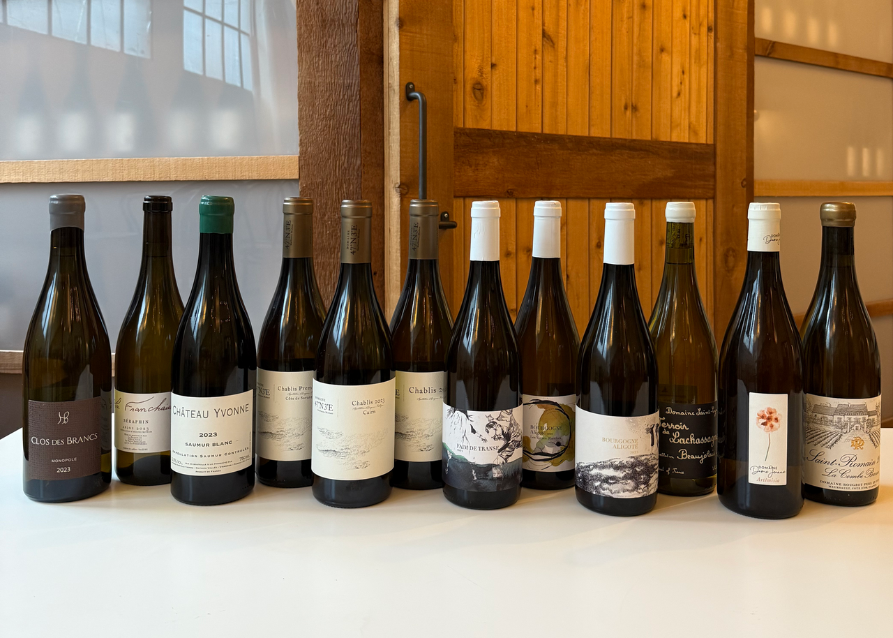 Row of wine bottles on a table with a wooden cabinet in the background